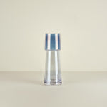 Clear glass vase with blue stripes on a beige background