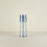 Clear glass vase with blue stripes on a beige background