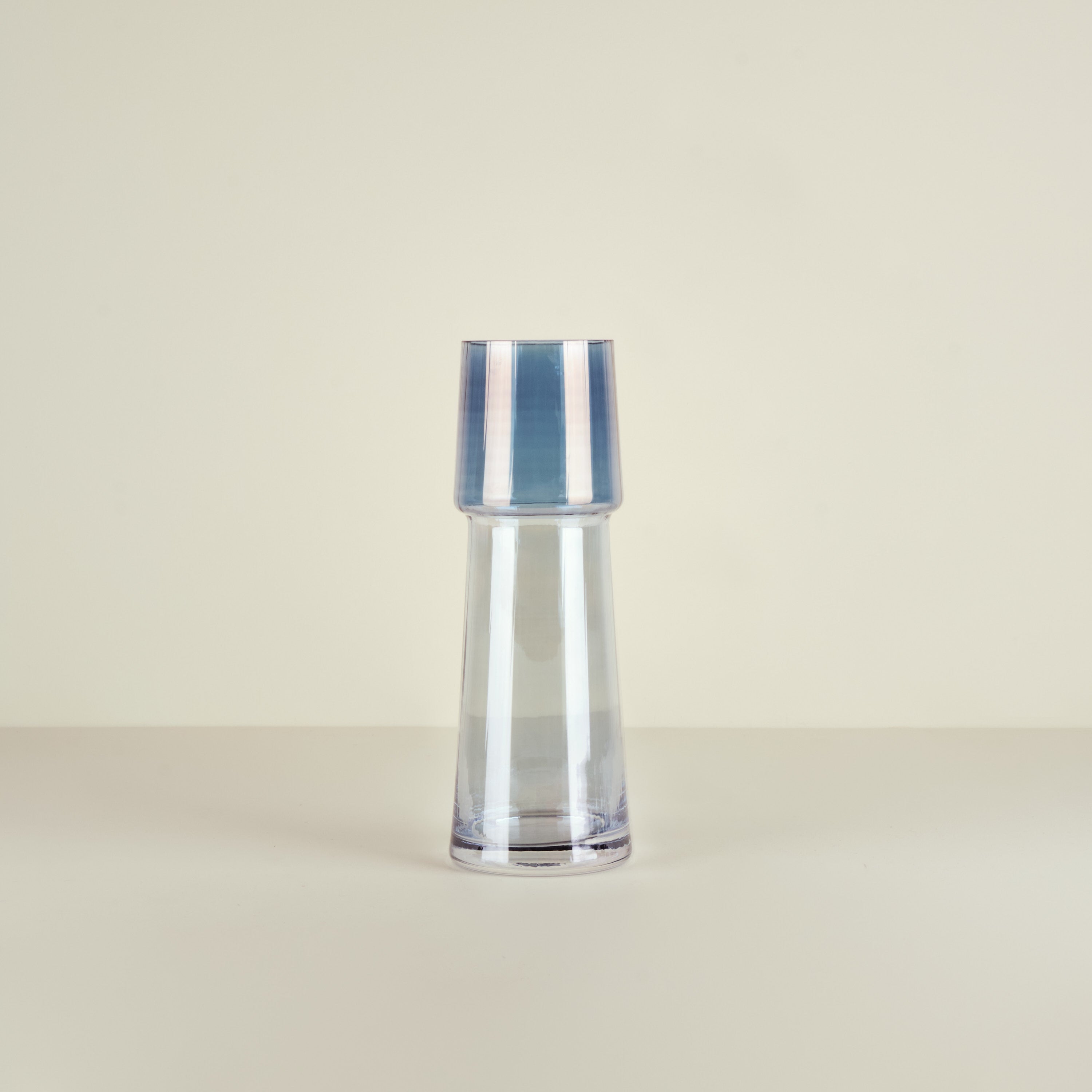 Clear glass vase with blue stripes on a beige background