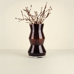 Black vase with decorative branches on a beige background