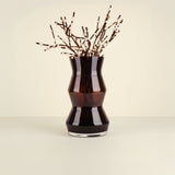 Black vase with decorative branches on a beige background