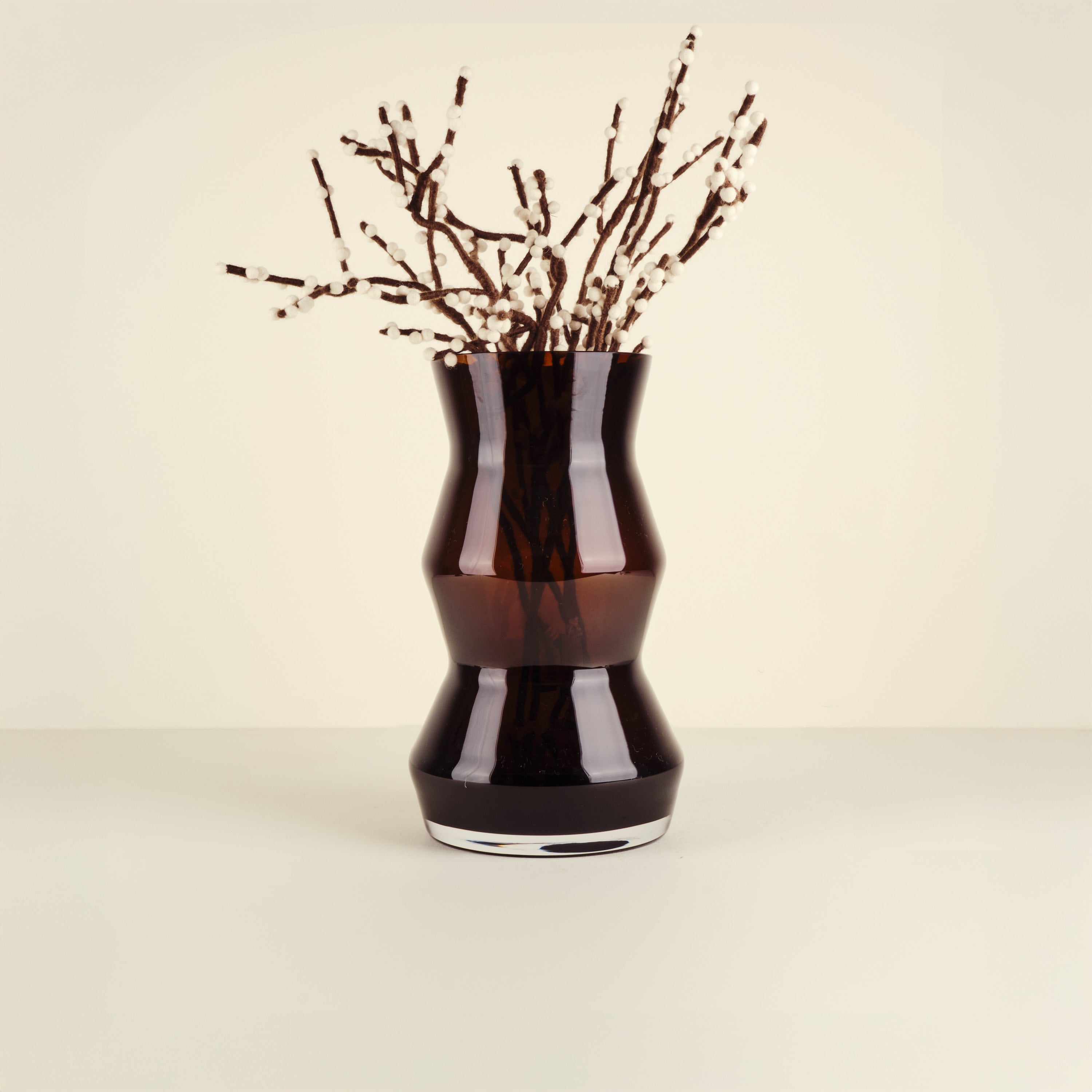Black vase with decorative branches on a beige background