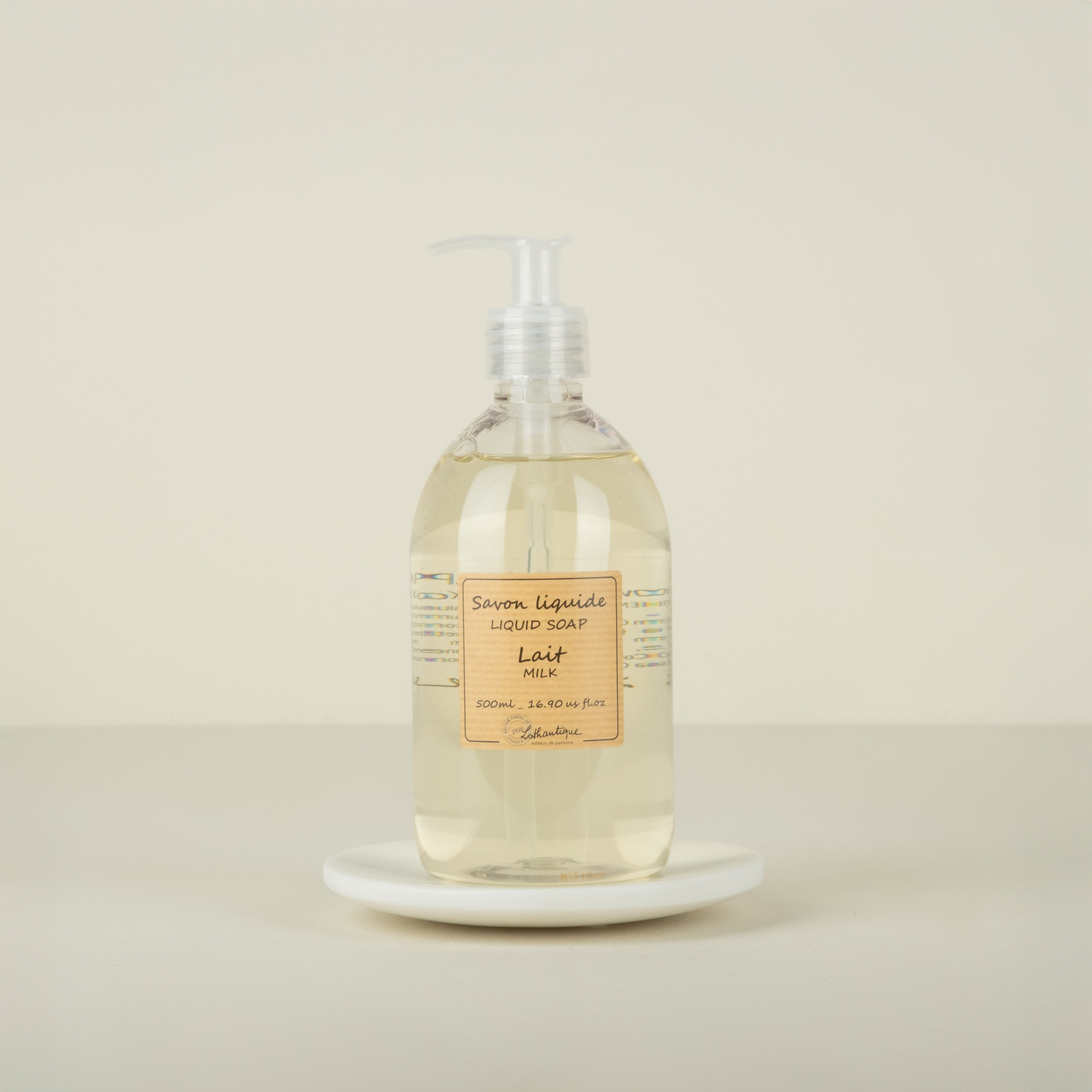 Bottle of liquid soap labeled 'Lait' on a marble plate with beige background