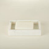 White soap bar in a rectangular soap dish on a beige background