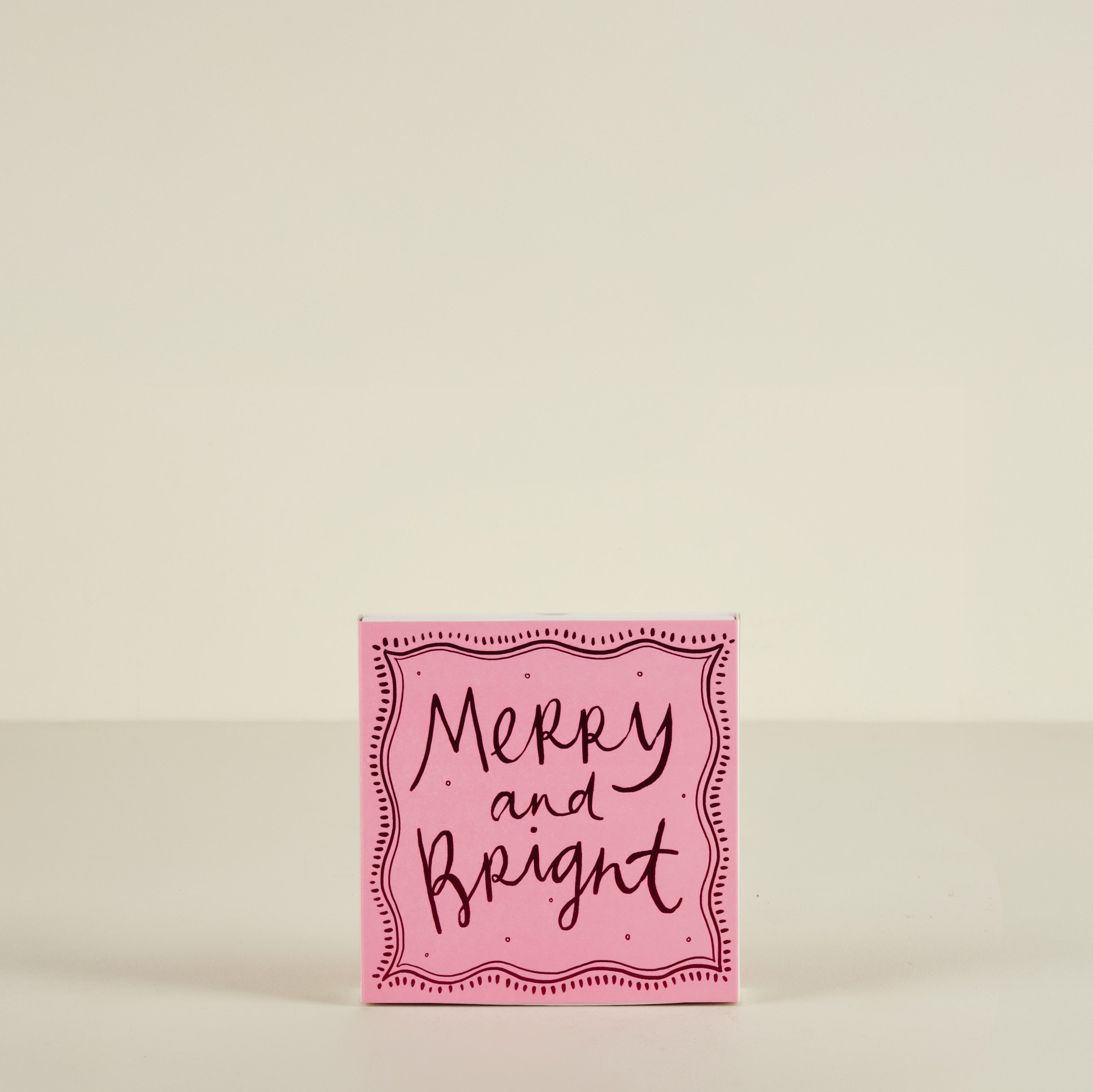 Pink card with 'Merry and Bright' text on a beige background