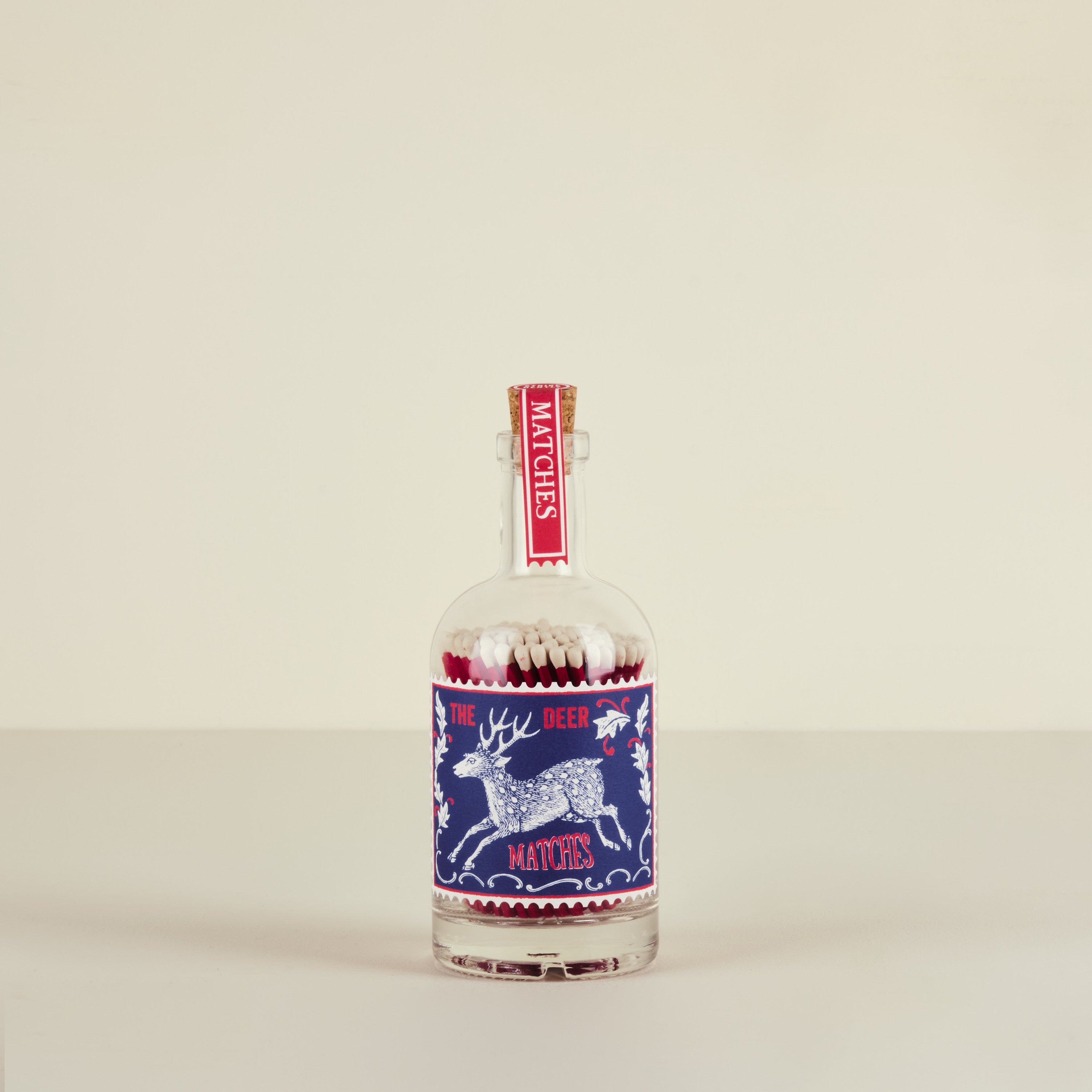 Matches in a glass bottle with a reindeer design on a beige background