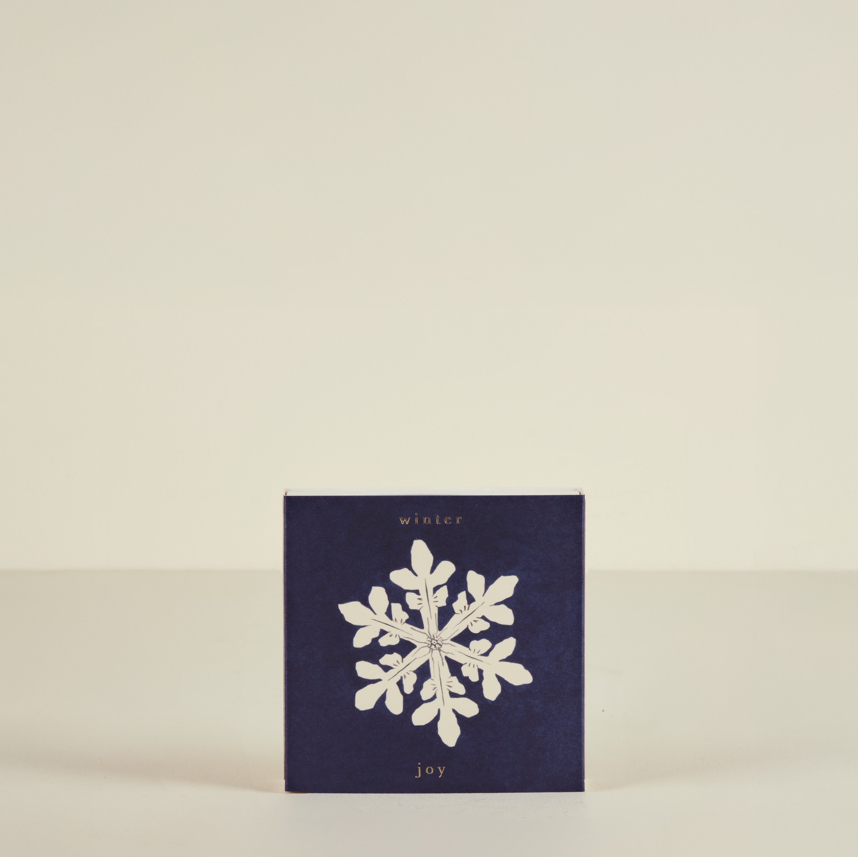Navy blue card with a white snowflake and 'winter joy' text on a beige background