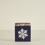 Matchbox with snowflake design and 'winter joy' text on a beige background