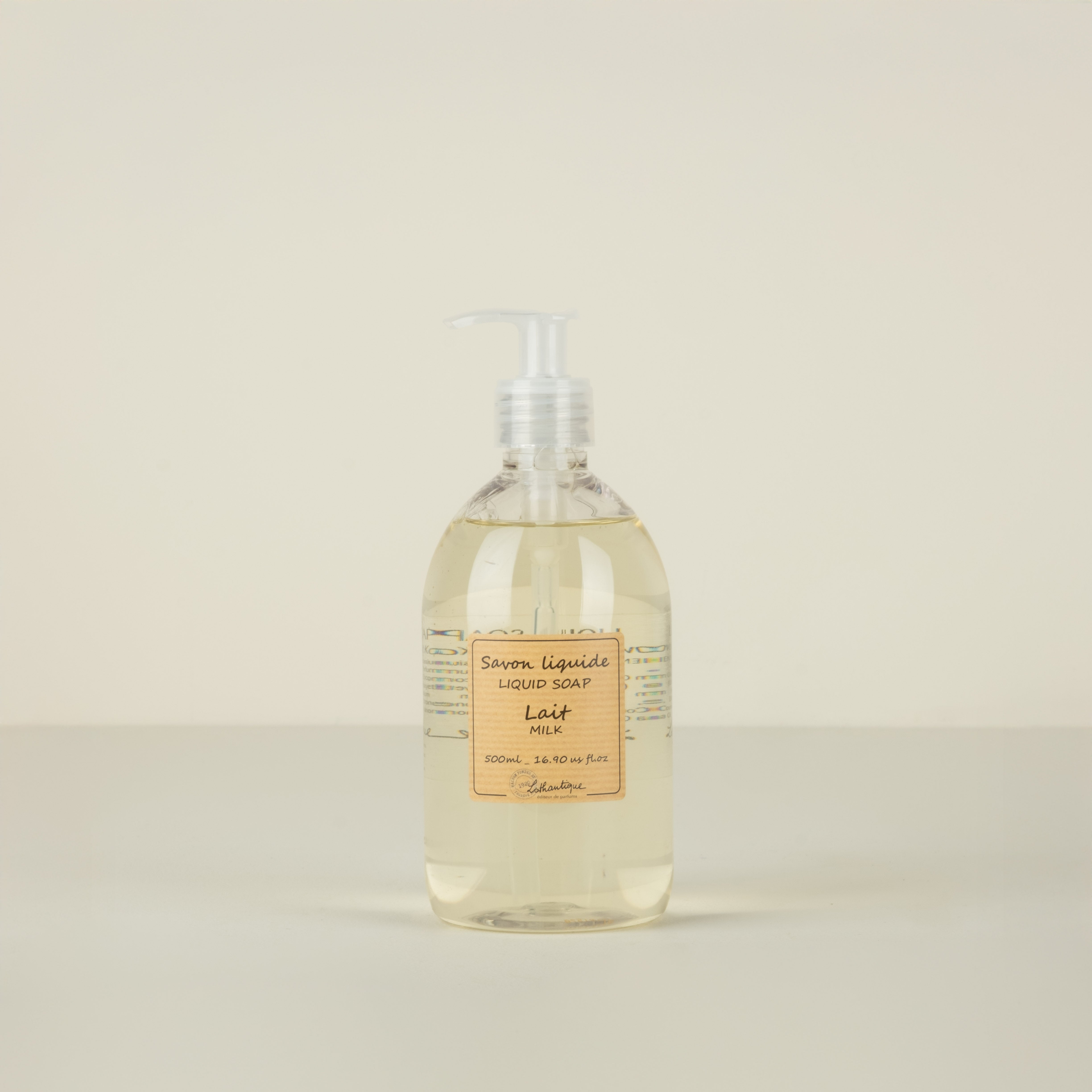 Bottle of liquid soap with a label on a beige background