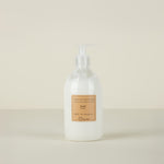 White lotion bottle with a pump and a label on a beige background