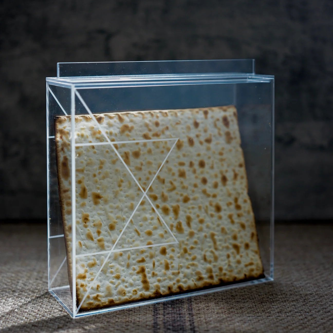 Stack of matzah in a clear plastic box on a dark background