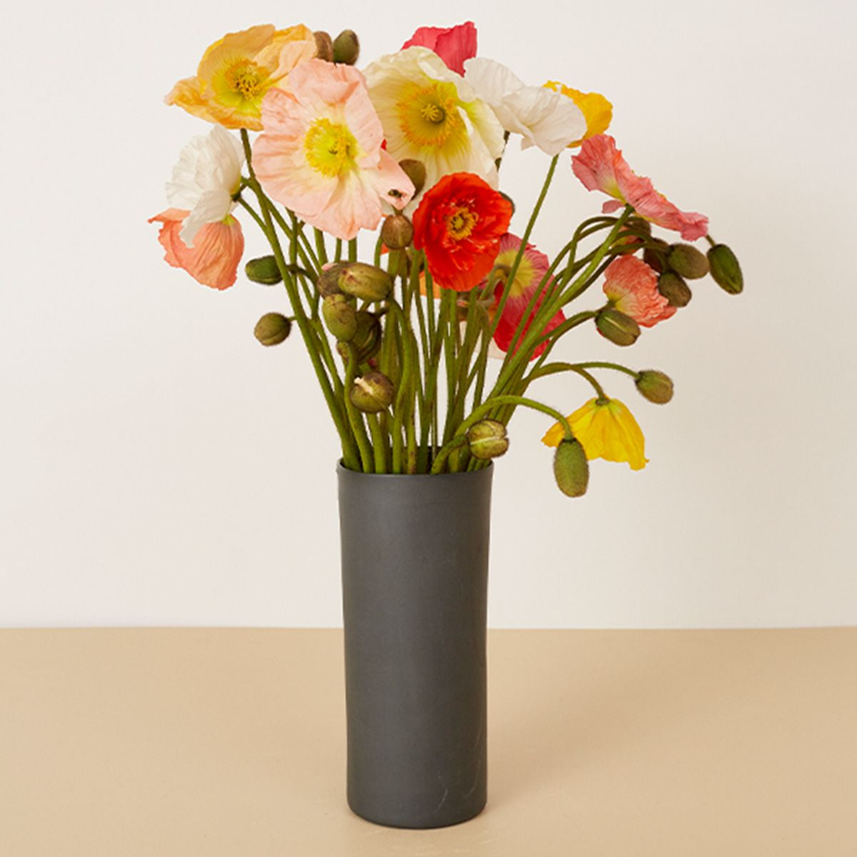 Vase with colorful flowers on a beige surface and white background