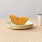 Melon slice on a plate with a cup and utensils on a wooden surface