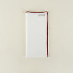 White napkin with red trim on a beige background