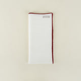 White napkin with red trim on a beige background