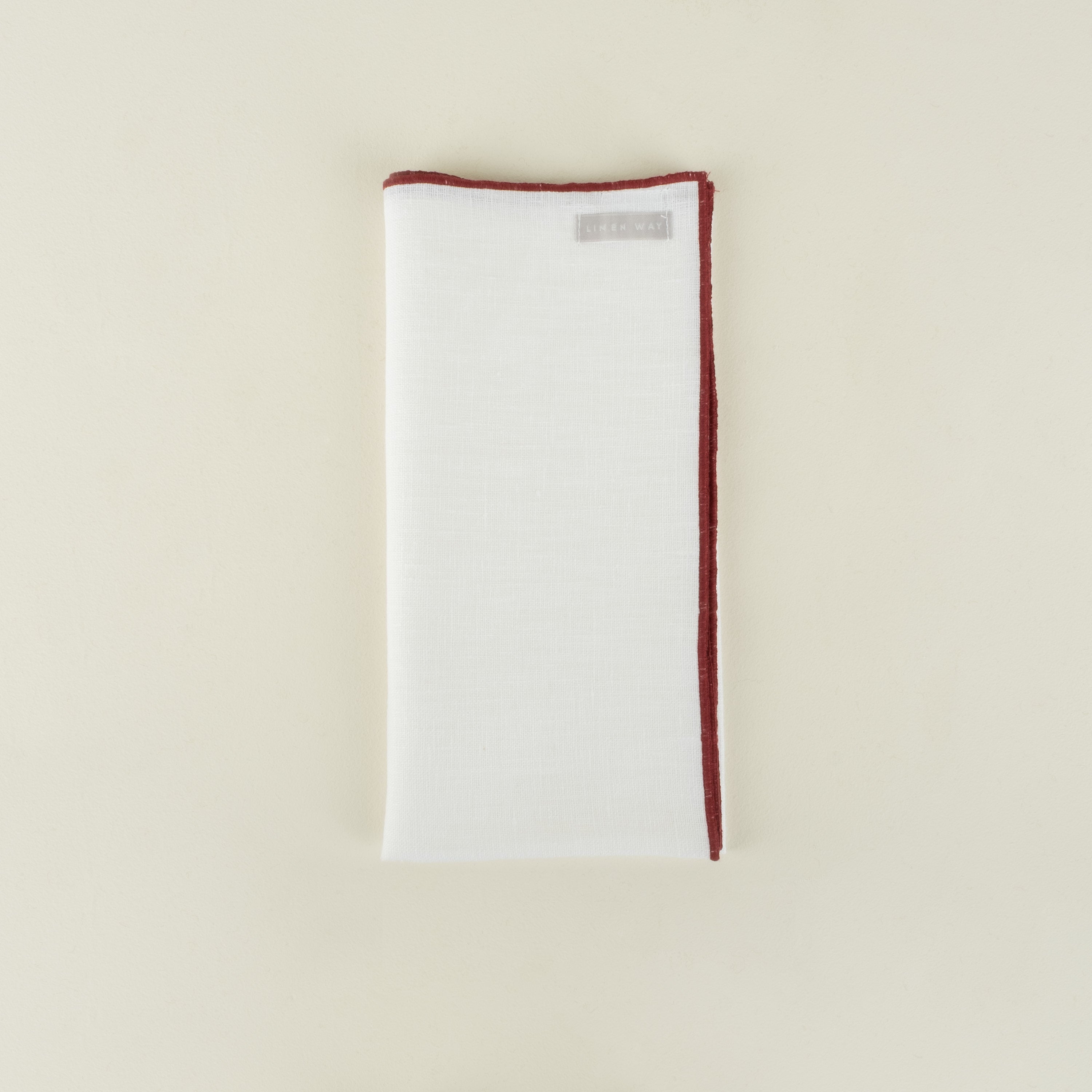 White napkin with red trim on a beige background