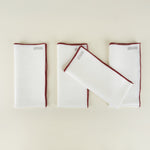 Set of white napkins with red borders on a beige background