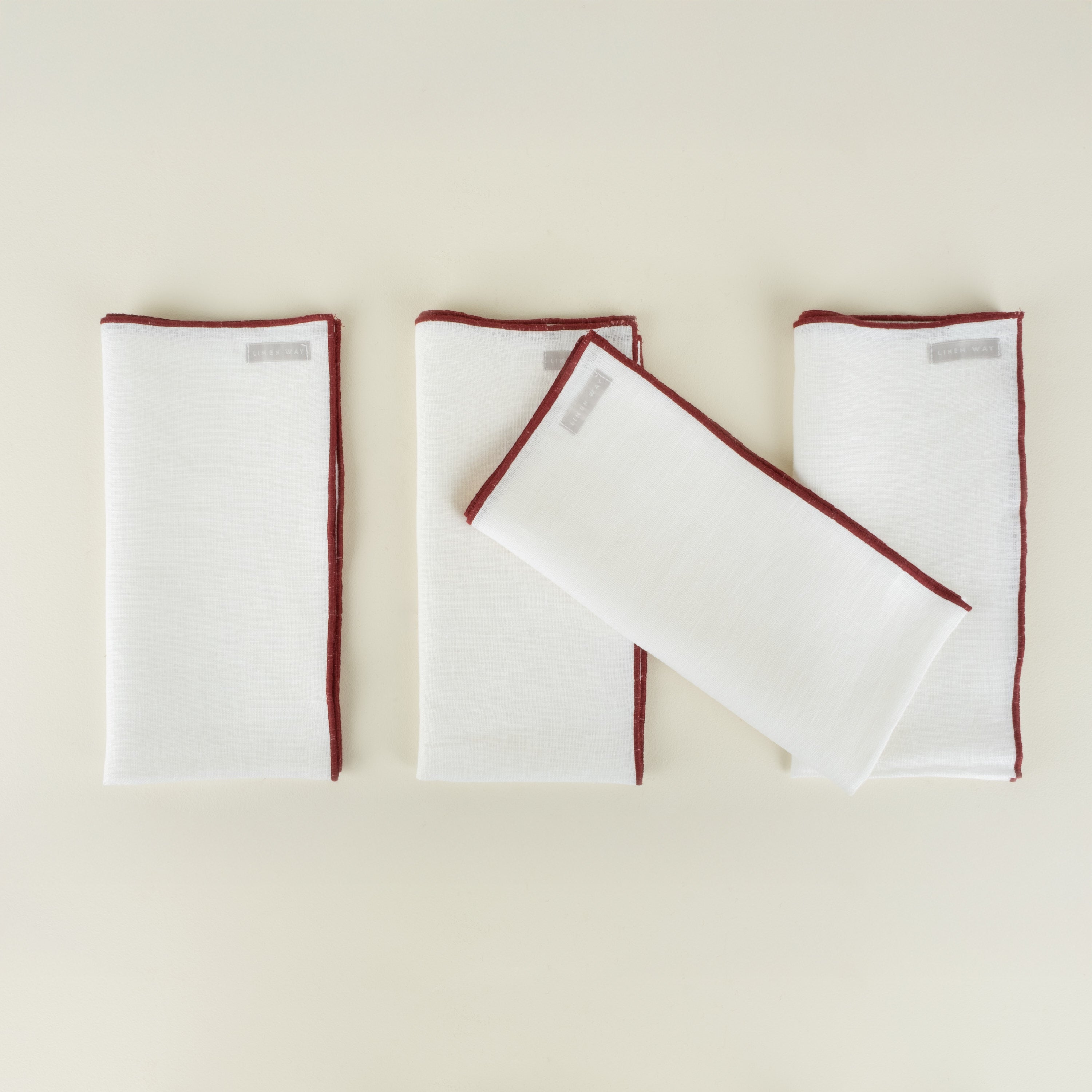 Set of white napkins with red borders on a beige background