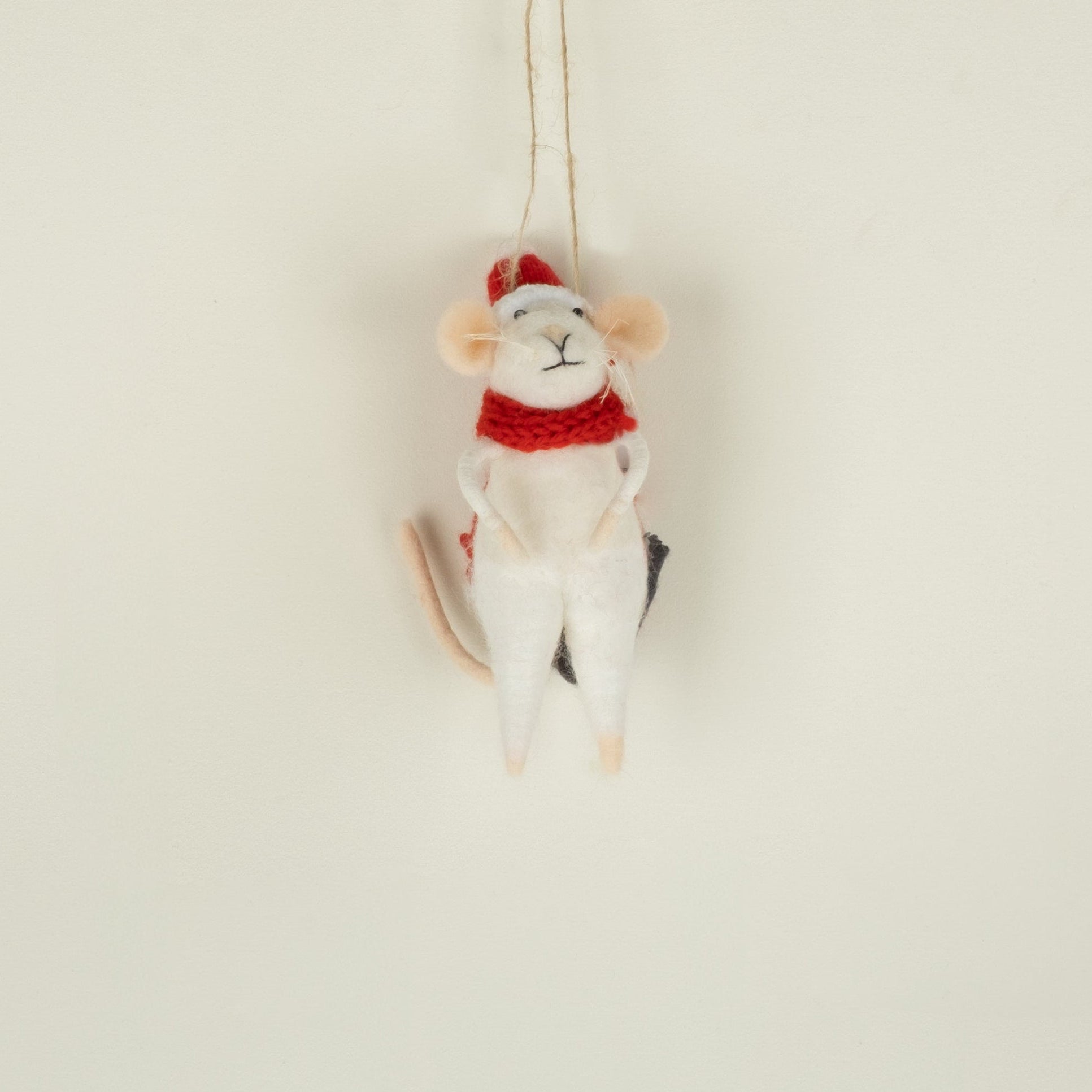 Mouse ornament with a red scarf and Santa hat hanging on a neutral background