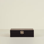 Black rectangular box with a gold emblem on a beige background