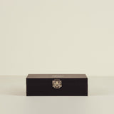 Black rectangular box with a gold emblem on a beige background