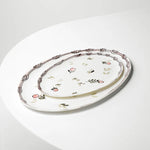 Decorative oval ceramic platter with floral patterns on a white surface