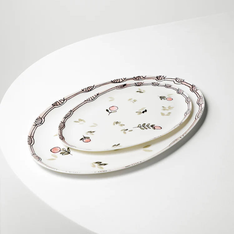 Decorative oval ceramic platter with floral patterns on a white surface