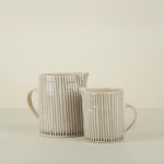 Two ceramic mugs with black striped patterns on a beige background