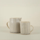 Two ceramic mugs with black striped patterns on a beige background
