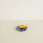 Two lemon wedges on a blue plate with a beige background
