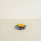 Two lemon wedges on a blue plate with a beige background