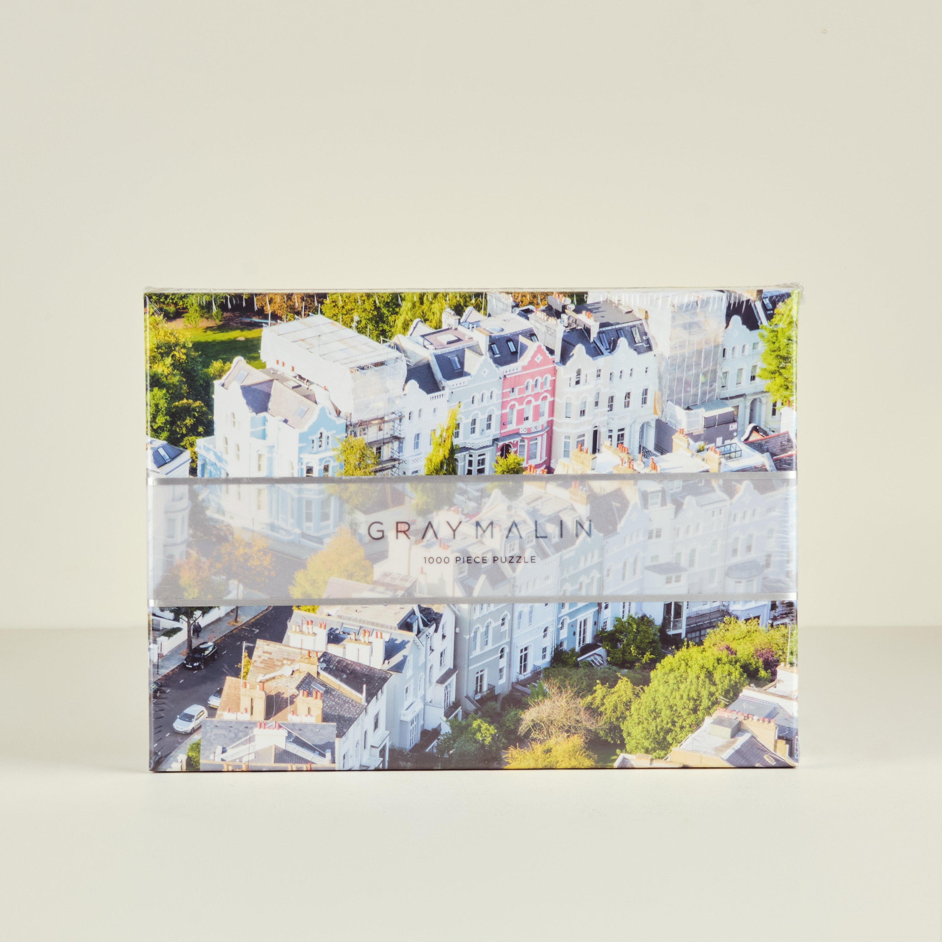 Gray Malin puzzle box with aerial view of buildings and trees on a beige background