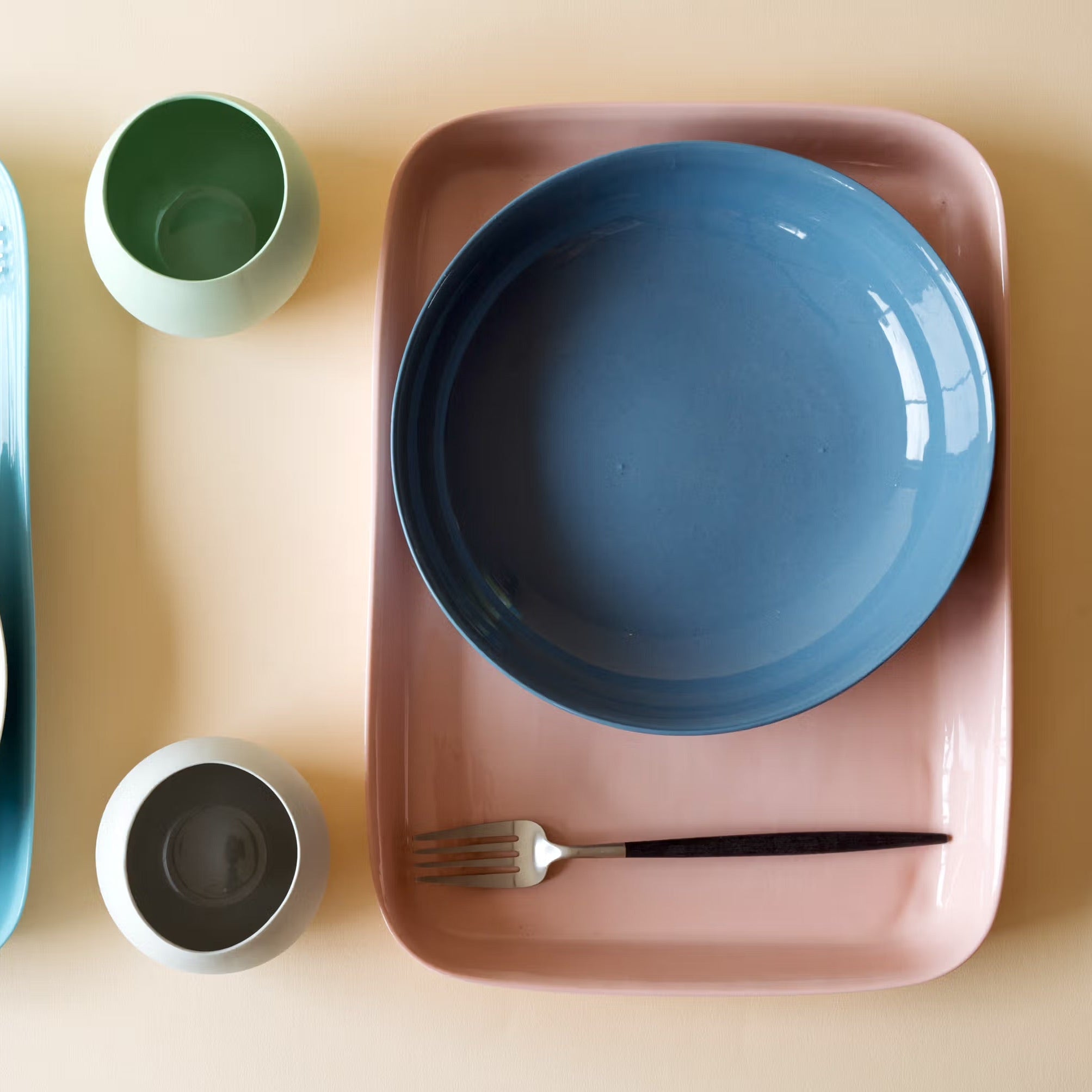 Set of ceramic plates and bowls on a beige surface with a fork and spoon.
