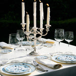 Dining table set with candles, glasses, and plates outdoors