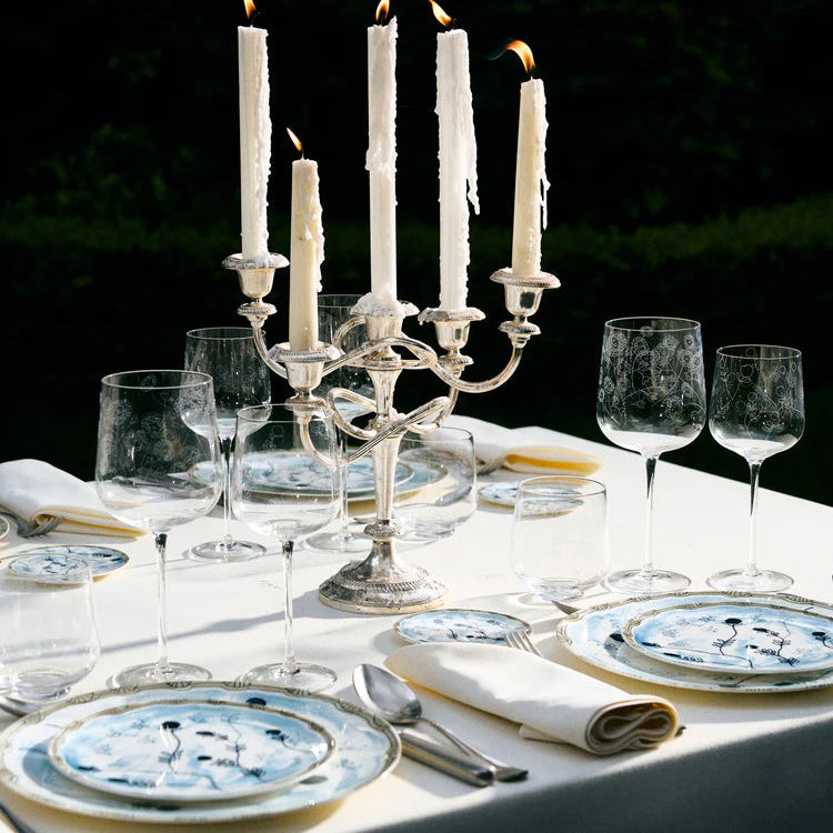 Dining table set with candles, glasses, and plates outdoors