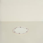 Round white plate with decorative border on a beige background