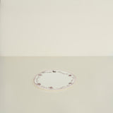 Round white plate with decorative border on a beige background