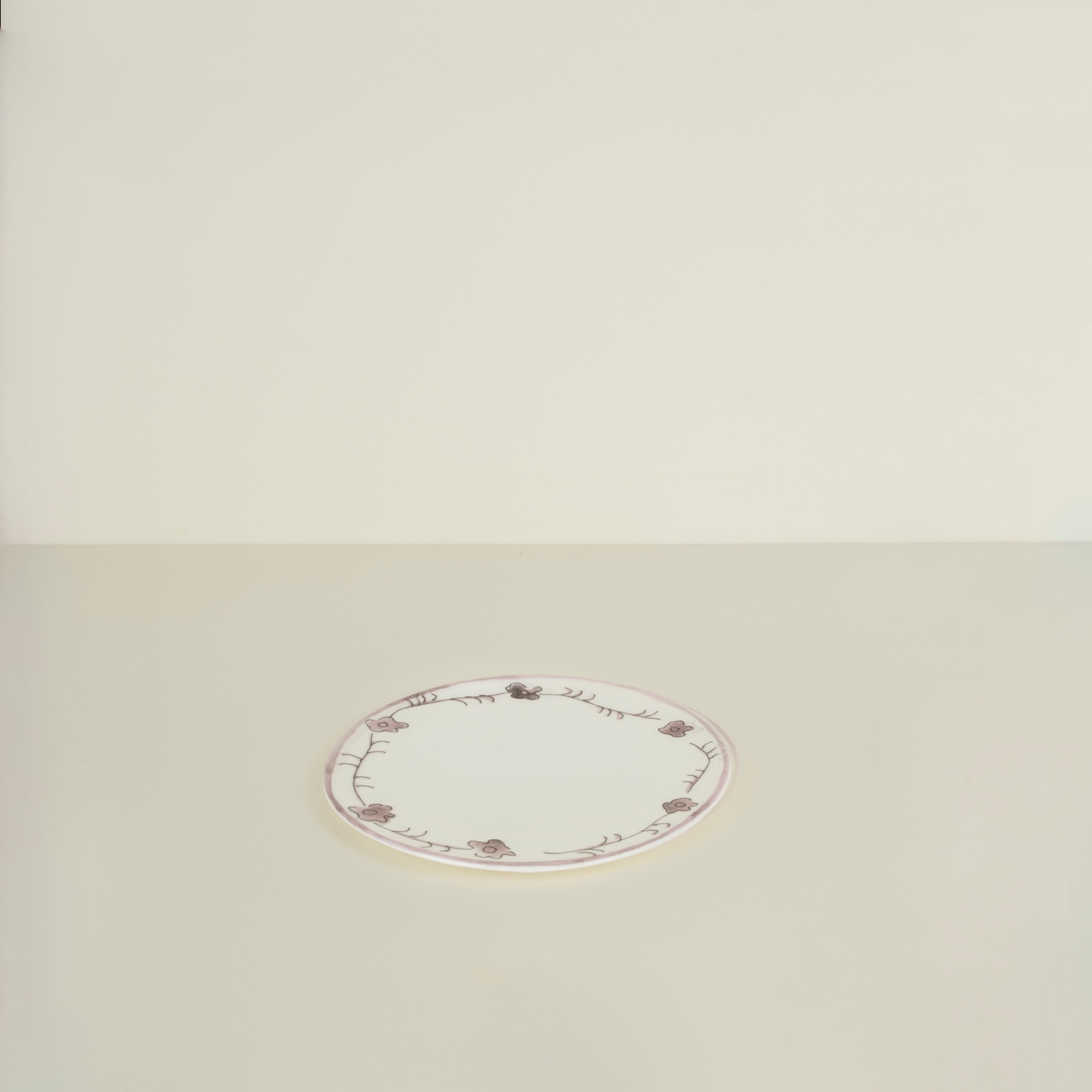 Round white plate with decorative border on a beige background