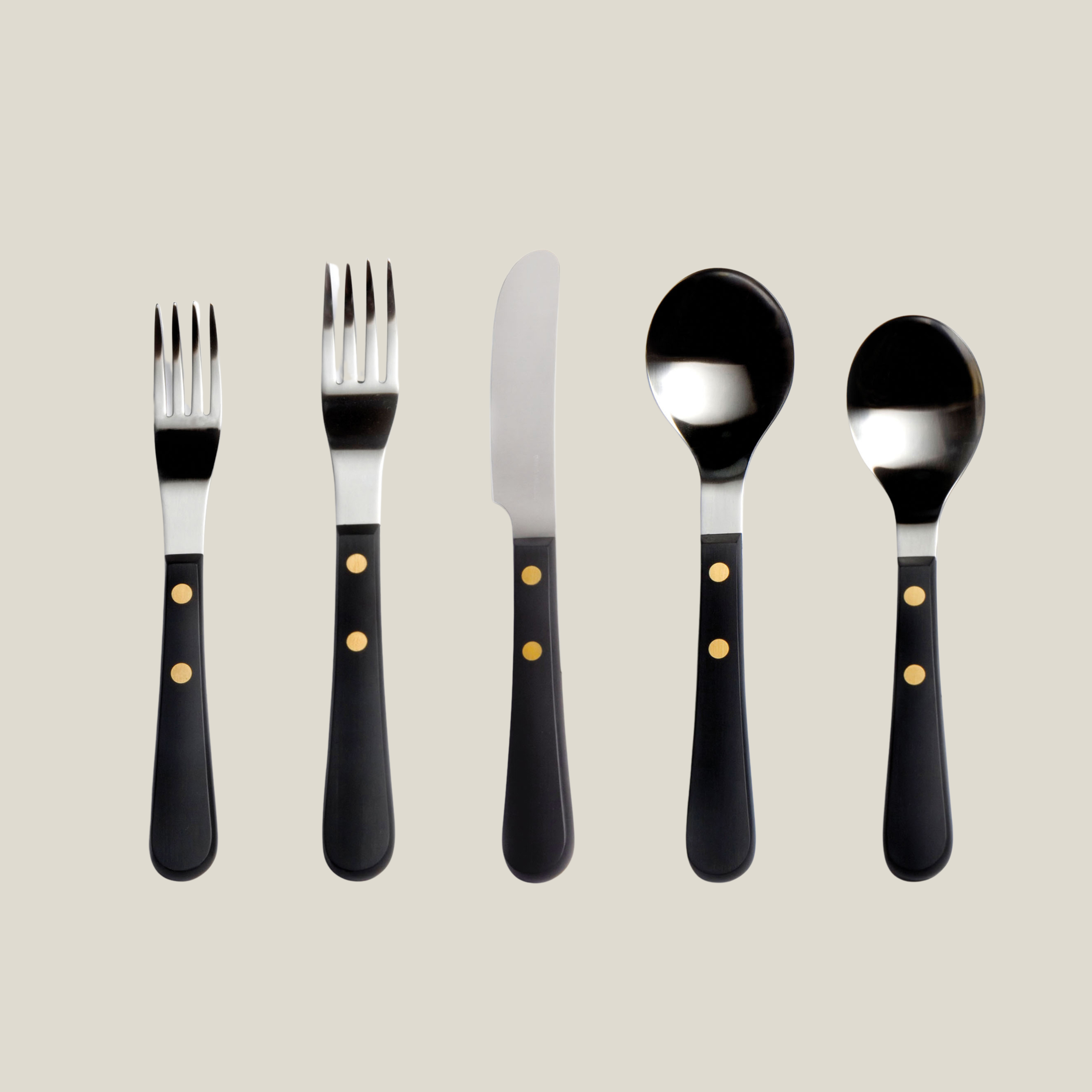 Set of black-handled cutlery with gold accents on a beige background