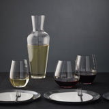 Wine decanter and glasses with white and red wine on a dark surface and background