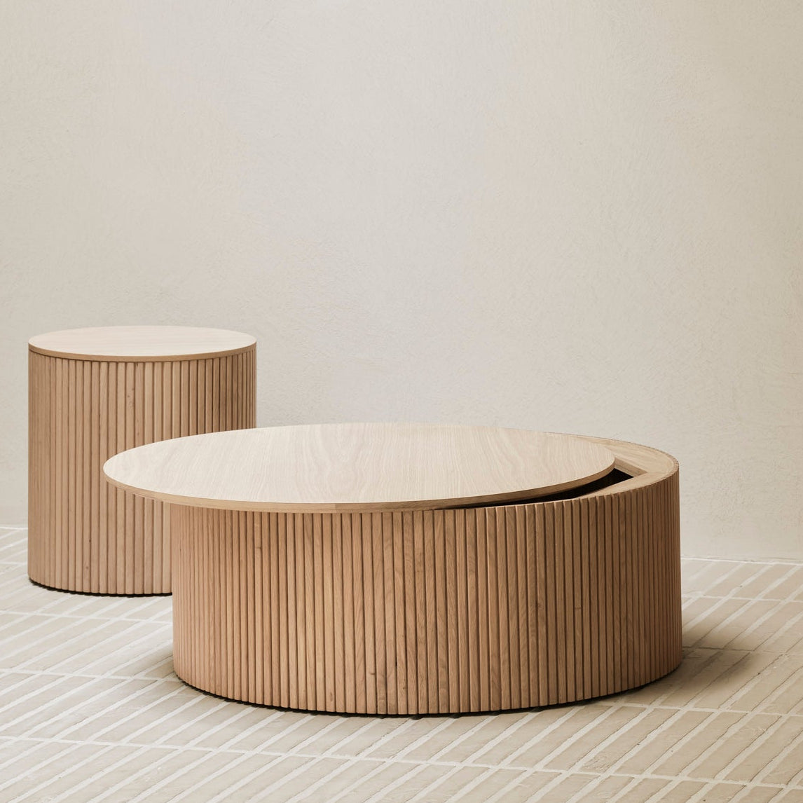 Three round wooden tables of varying sizes on a neutral background