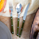 Set of cutlery with green handles on a wooden surface