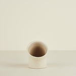 Small ceramic cup on a beige background