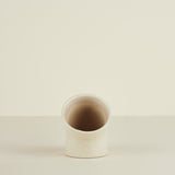 Small ceramic cup on a beige background