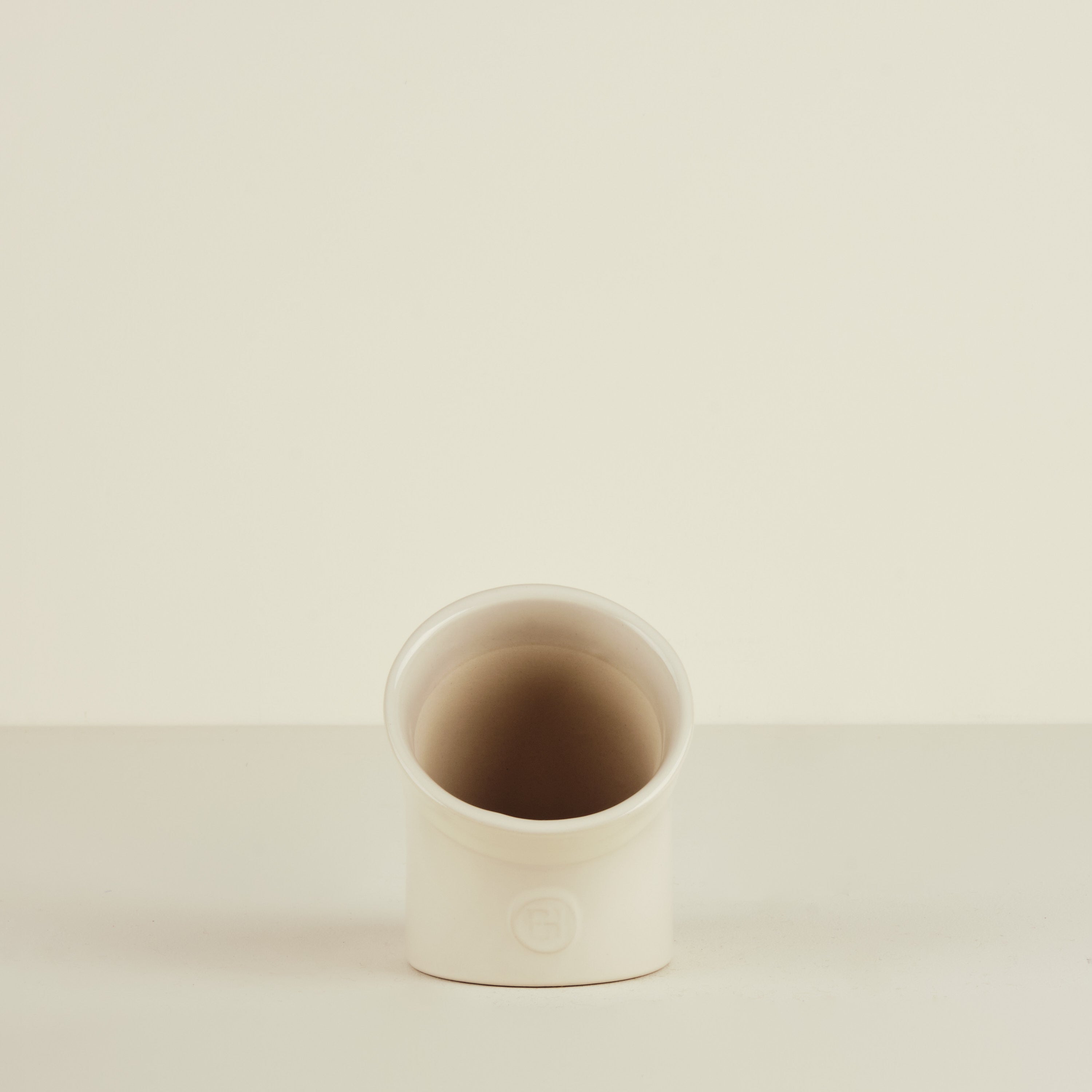 Small ceramic cup on a beige background