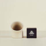 White ceramic container and black box with 'Sel Saint Laurent' text on a beige background