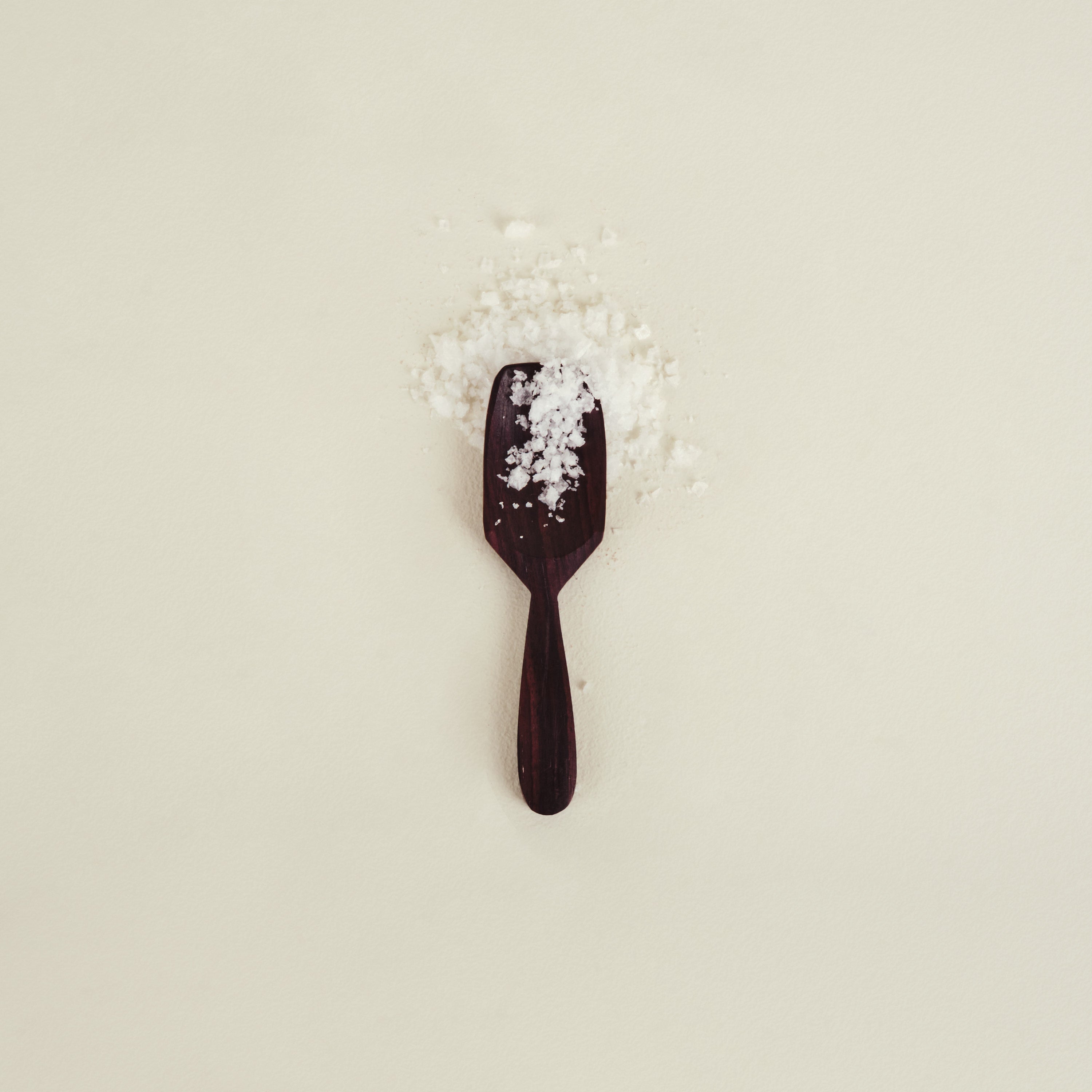 Black spoon with salt on a beige background