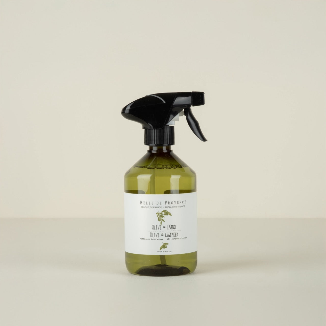 Green spray bottle with black nozzle on a beige background