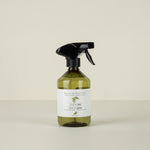 Green spray bottle with black nozzle on a beige background