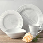 White ceramic dinnerware set with a rose on a wooden surface